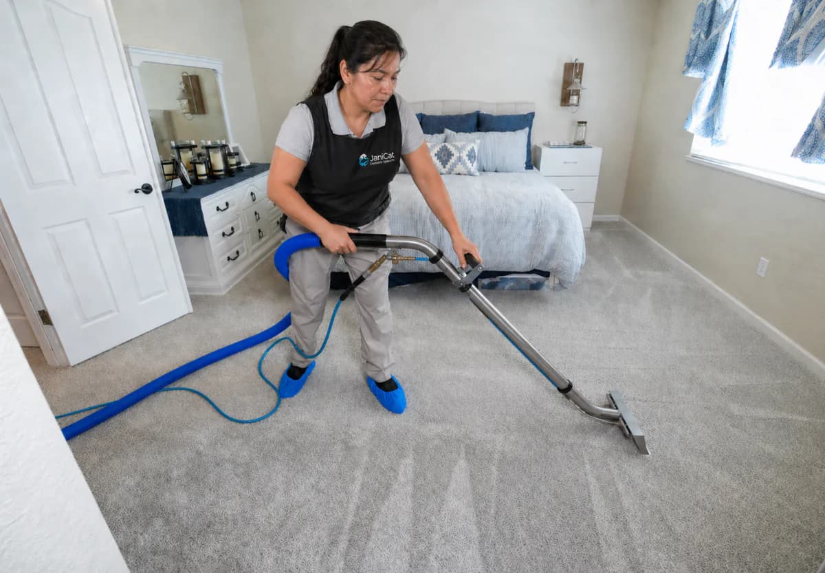 Janicat team member deep-cleaning a bedroom carpet